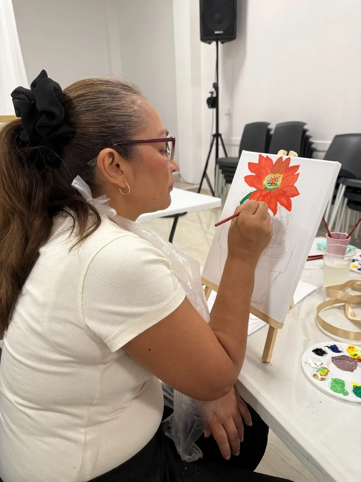 Participante pintando una flor sobre el lienzo