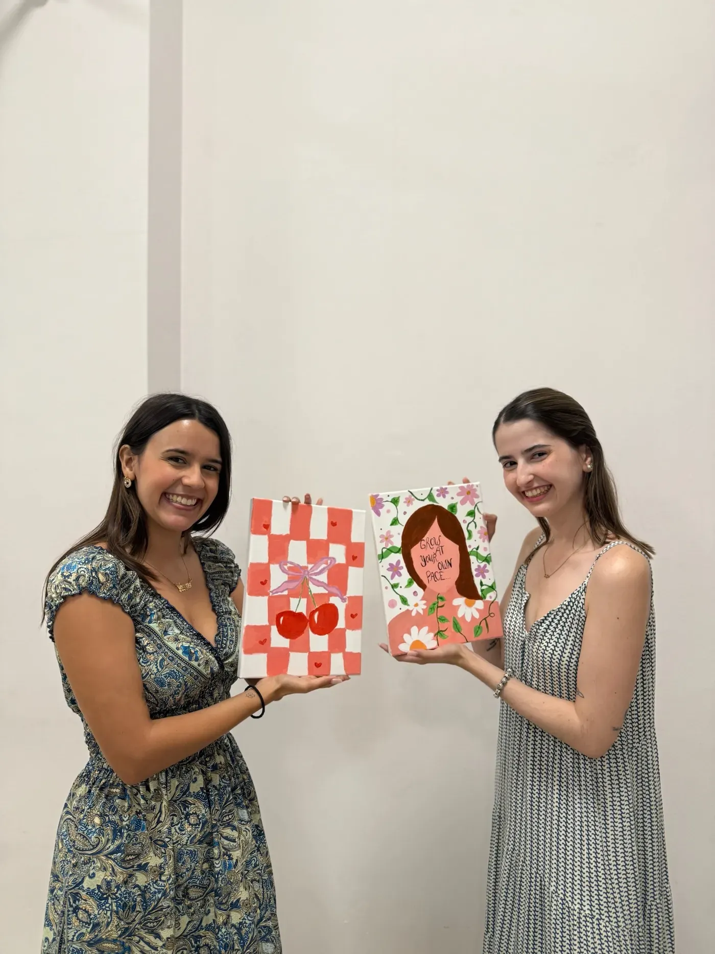 Dos participantes sujetando sus obras terminadas